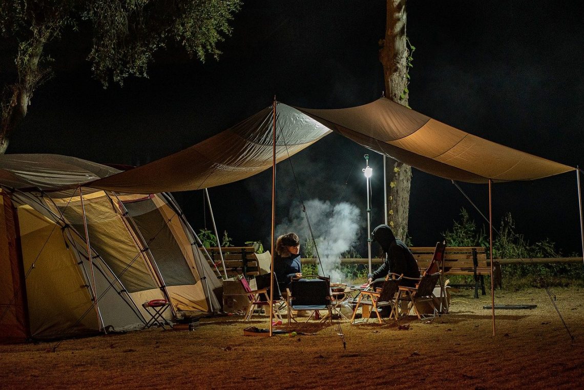 deux personnes attablées devant une tente de camping