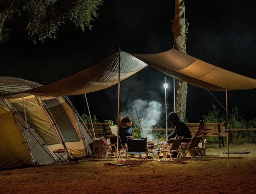 deux personnes attablées devant une tente de camping